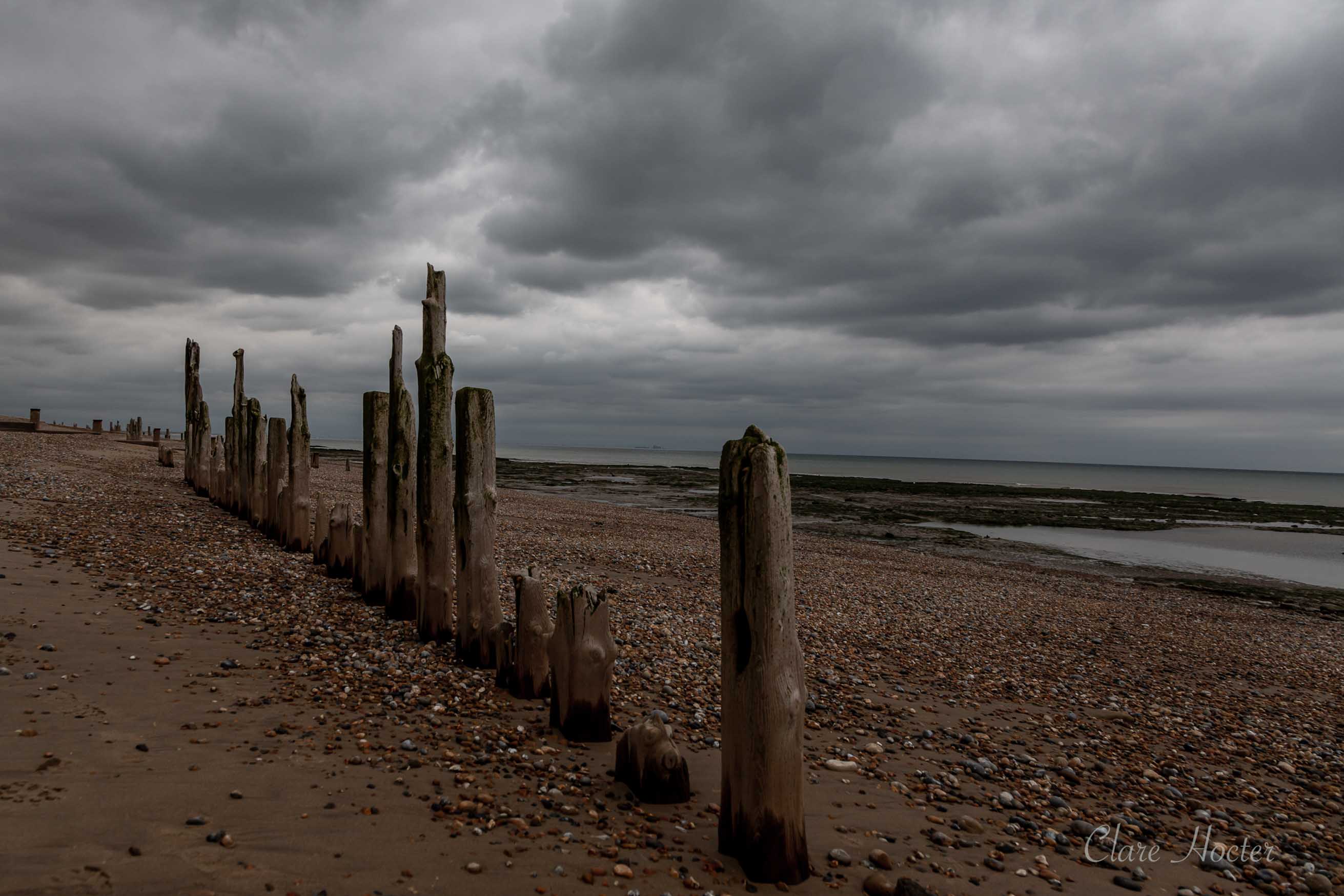 Wooden poles, dramatic sky, pett level beach
